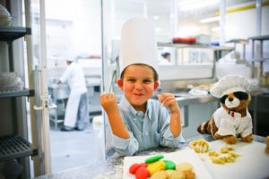 Child in chef's hat during cooking lesson
